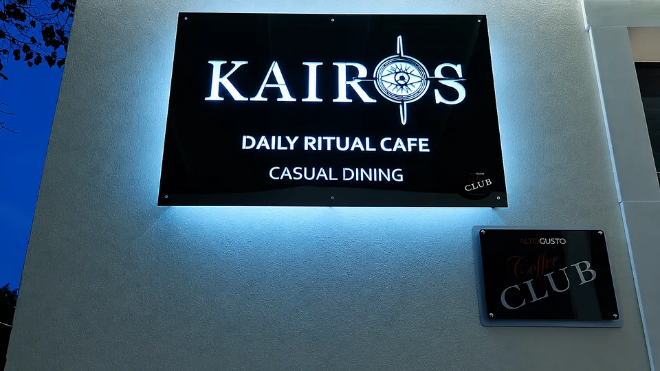 L'insegna luminosa Kairos Daily Ritual Cafe all'ingresso del locale